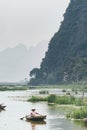 Ninh Binh, Vietnam - May 2019: Vietnamese woman in a wooden rowing boat going through Trang An nature park