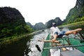 Ninh Binh, Vietnam - October 14, 2010 : Activity downstream on boat with vietnamese using foot paddle and view limestone mountain