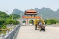 Farmer on old rusty tractor driving in front of ancient gate near Ninh Binh, Vietnam