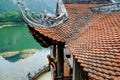 Ninh Binh / Vietnam, 08/11/2017: Woman leaning out of a Buddhist temple enclosure with traditional ornamental tiled roof in the