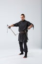 A ninja man, in a black kimono, holds two old rusty blades by crossing their blade tip. Royalty Free Stock Photo