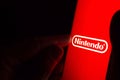 Nintendo logo on a red smartphone screen in a dark room and a finger touching it