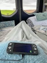 A Nintendo Switch on a persons lap while relaxing in a camper van looking toward the back window