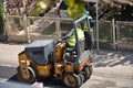 Small pneumatic tired roller compactor at asphalt pavement works for road repairing with workers