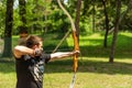 Masterful Archery Display: Young Archer Takes Aim in Forest at Medieval Knight Festival