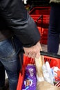 Detail of woman`s hand holding plastic basket with groceries waiting in line to pay in Maxi, big market retail company in Serbia