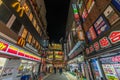 Colorful busy Street and Neon Billboards. People passing along Shops and restaurants around Shinjuku Station at night