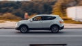 Nissan Qashqai driving on the country road at sunset. Side view of white Nissan Rogue Sport SUV in motion on the background of Royalty Free Stock Photo