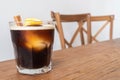 Nitro cold brew coffee with ice, cinnamon and lemon on wooden table and chairs set as a special drink menu ready to serve for the Royalty Free Stock Photo