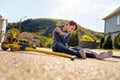 njury. A teenage boy lies on the ground next to a scooter, rubbing his bruised shoulder. Outdoor. Concept of extreme sports and