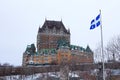 View of Frontenac Castel Chateau de Frontenac, in French in winter under the snow with a Quebec flag waiving.