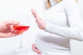 No alcohol during pregnancy. Young pregnant woman refuses to drink wine, making stop gesture to glass, free space