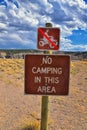 NO CAMPING IN THIS AREA warning sign, No ATV graphic sign near Starvation State Park Reservoir around bridge over lake with rain c Royalty Free Stock Photo