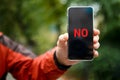 NO on the smartphone screen. A smartphone with the word NO on the smartphone screen in a man& x27;s hand. Message using a Royalty Free Stock Photo