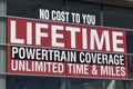 NO COST TO YOU LIFETIME POWERTRAIN COVERAGE UNLIMITED TIME AND MILE sign at a car dealership