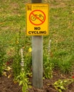 No Cycling Yellow sign in outdoor park for visitor safety.