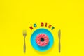 No diet and Pink donut on blue plate and knife fork on yellow background.