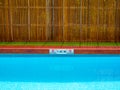 No diving sign and pool depth sign on pool edge on outdoor swimming pool on wooden fence background Royalty Free Stock Photo