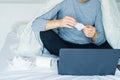 No face caucasian sick man holding used napkin tissue after blowing his nose sitting on the bed under a warm blanket and working Royalty Free Stock Photo