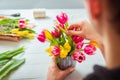 No face young man making spring bouquet using tulips. Online self-education of floristry. Learning flower arranging. Flowers Royalty Free Stock Photo