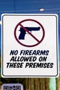 No firearms allowed on these premises sign closeup on door to US glass business with reflections