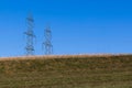 no life without electricity. two big power pylons behind a green hill in a beautiful cloudless blue sky  without people in the Royalty Free Stock Photo