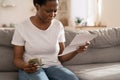 African woman frustrated about lack of finances, feeling anxiety about overdue mortgage payment.