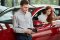 No money. man near new car looking empty pocket, while his wife doing selfie in car Royalty Free Stock Photo