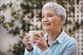 No more rush, just pure relaxation. a senior woman having coffee in the garden at home.