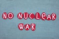No nuclear war, pacifist slogan composed with red colored stone letters over green sand