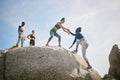 No one can do it alone. a woman helping her friend climb a boulder during a workout.