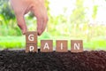 No pain no gain concept. Hand changing pain word to gain in wooden blocks on natural background.