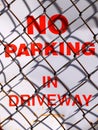 No Parking in Driveway Sign with Chain Link Fence Shadows Royalty Free Stock Photo