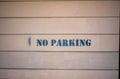 No parking painted in black on side or exterior of garage with horizontal wood pannels in the downtown city or neighborhood