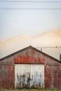 No Parking painted on old wooden doors of rusty red corrugated iron shed on misty morning