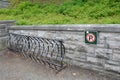 No parking sign with metal bike rack and stone wall