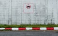 A no parking sign on the white concrete wall at the road in the carpark