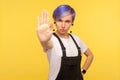 No, prohibited! Portrait of serious hipster woman showing stop gesture limit sign. yellow background, studio shot