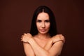 No retouch photo of temping self confident woman with brunette hairdo embrace her shoulders  on dark brown color Royalty Free Stock Photo