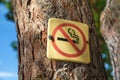 A sign indicating the prohibition of smoking attached to a tree