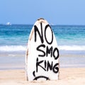 No Smoking warning sign on white surfboard at the beach in summer, concept of sea environmantal protection design, copy space,