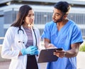 No stranger to troubled times. two young doctors checking some paperwork while outside in the city. Royalty Free Stock Photo