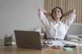 Young happy italian woman with hands behind head relaxing at workplace in home office