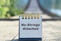 No strings attached text written on white note with blurred background of hanging bridge