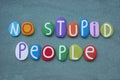 No stupid people, creative slogan composed with multi colored stone letters over green sand