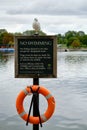 No swimming sign and orange lifebuoy at the Serpentine Lake in Hyde Park in London, UK Royalty Free Stock Photo