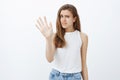 No thanks, pass. Portrait of displeased unhappy european girl with blond hair in stylish outfit, raising palm in stop or