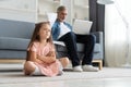 No Time For Child. Grey-haired dad busy with laptop, working online at home, sad bored offended daughter sitting near by Royalty Free Stock Photo