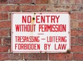 No trespassing sign mounted on brick wall