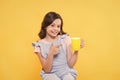 No use crying over spilt milk. Drink enough water. Girl kid hold mug yellow background. Carefree smiling child pointing